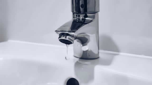 Verchromter Wasserhahn über einem weißen Waschbecken