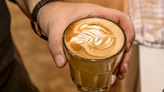 Hände halten ein Glas Latte macchiato