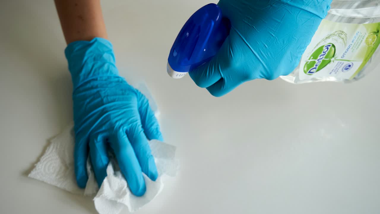 Person mit Handschuhen reinigt eine Wand mit einem Schwamm