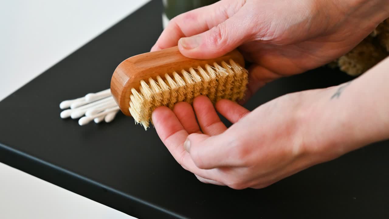 Hände halten eine Holzbürste zur Schuhreinigung